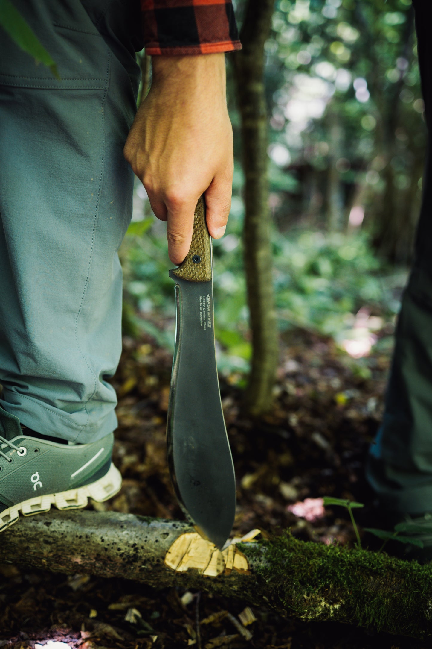 Person holding a knife in a forest setting
