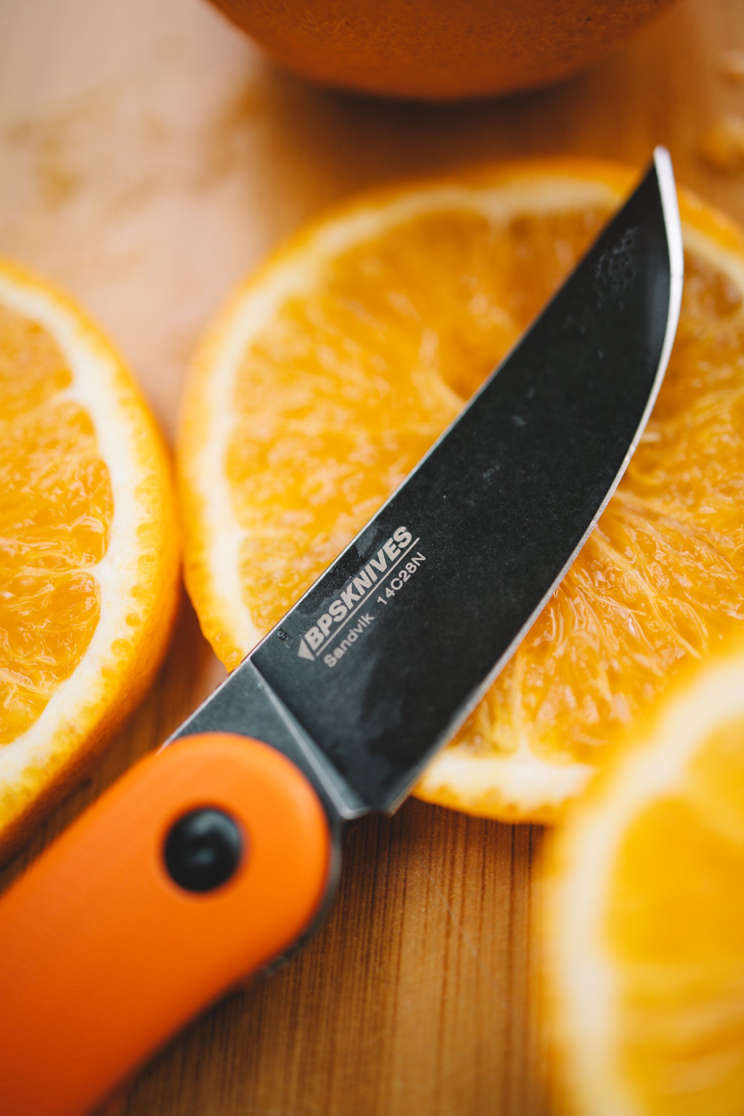 Knife with orange handle on sliced oranges on a wooden surface