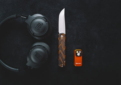 JBL headphones, knife, and orange lighter on a dark surface