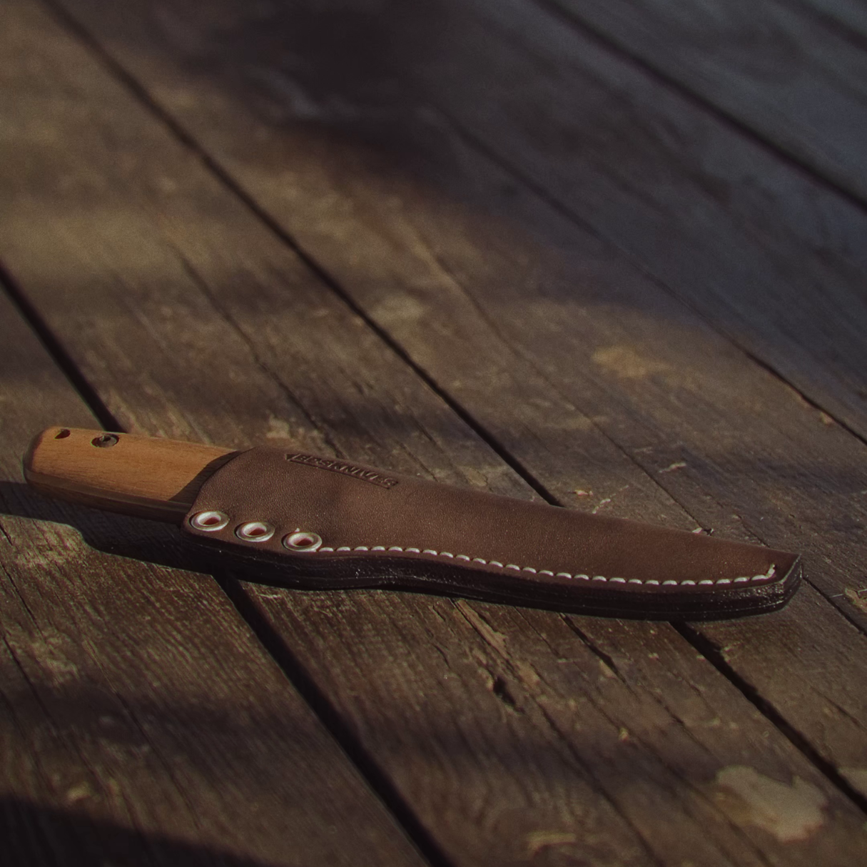 Brown leather knife sheath on a wooden surface