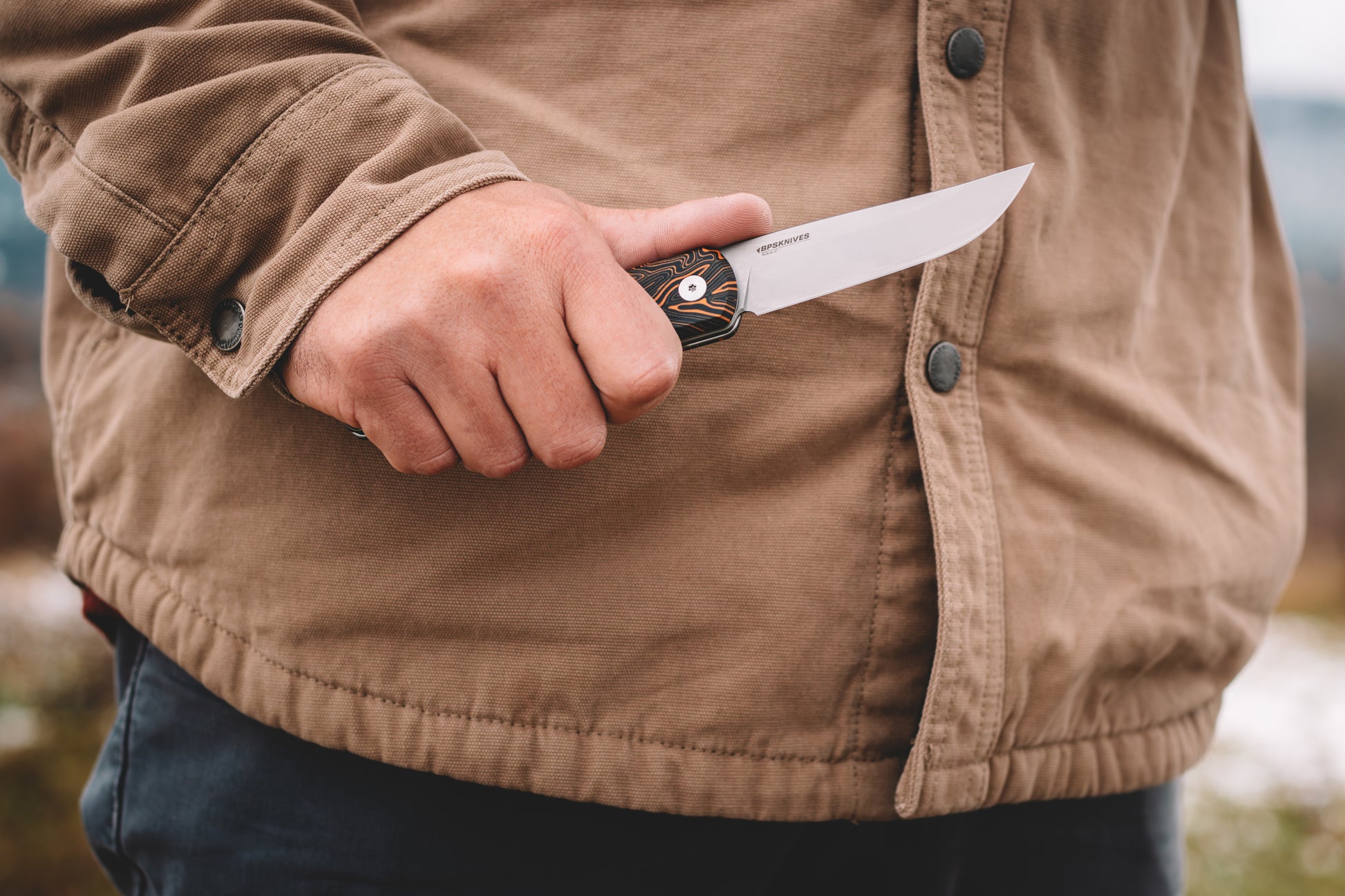 Person holding a knife with a blurred natural background