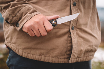 Person holding a knife with a blurred natural background