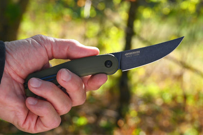 Hand holding a knife with a blurred natural background