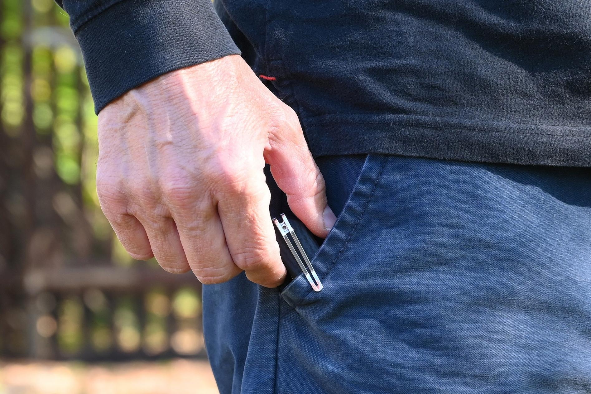 Person pulling a knife from their pocket outdoors