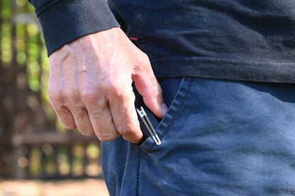 Person pulling a knife from their pocket outdoors